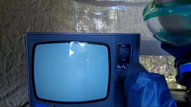 Людина в захисному костюмі вмикає старий телевізор. Пост-апокаліпсис — стокове відео