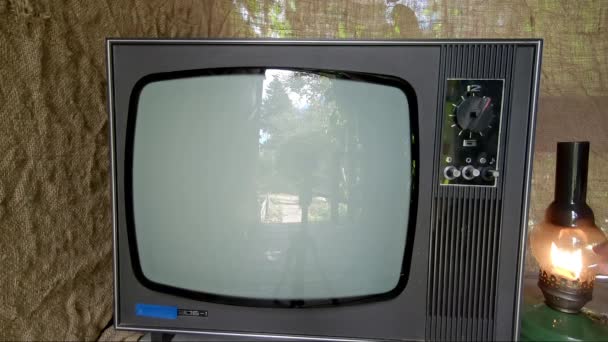 Человек с керосиновой лампой включает старый ретро-телевизор — стоковое видео