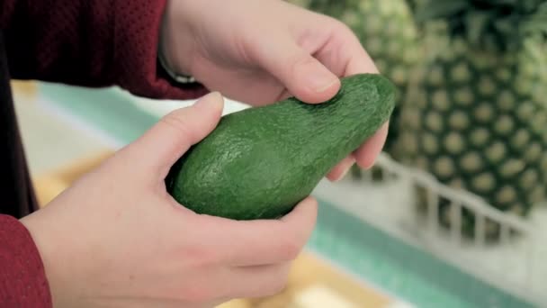 La ragazza al supermercato sceglie l'avocado. Primo piano colpo di mano — Video Stock