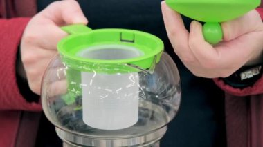 Dükkandaki kız bitki demlemek için cam çaydanlık seçiyor.