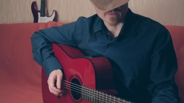 Mies cowboy hattu soittaa punaista akustista kitaraa ja laulaa — kuvapankkivideo
