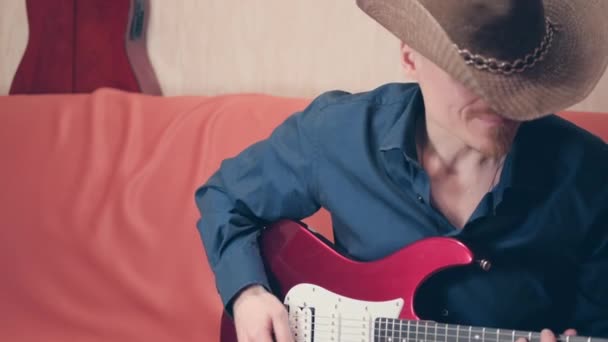 काउबॉय हॅटमध्ये काकेशियन माणूस इलेक्ट्रिक गिटार वाजवतो — स्टॉक व्हिडिओ
