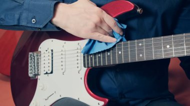 Erkek elleri elektro gitar silme aletini tozdan temizler.