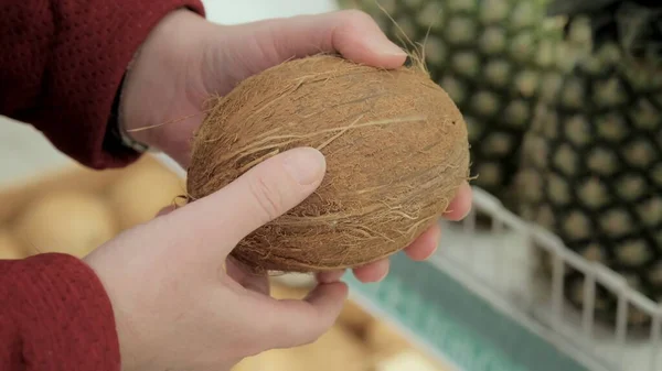 A rapariga escolhe um coco num supermercado. Fechar tiro — Fotografia de Stock