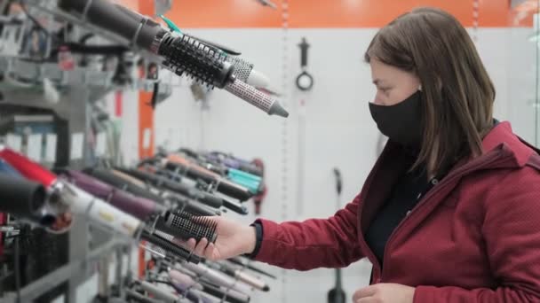 Девушка в медицинской маске покупает фен в магазине — стоковое видео