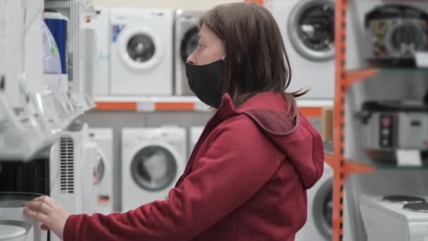 Девушка в медицинской маске покупает увлажнитель в магазине — стоковое видео