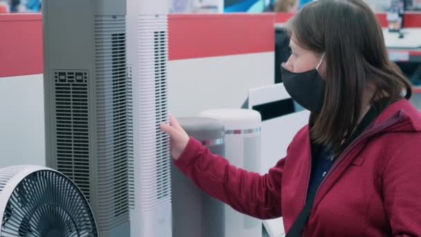 Meisje met medisch masker koopt verwarming in de winkel — Stockvideo