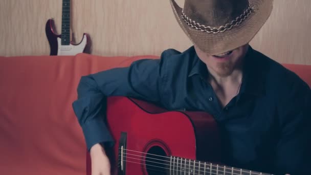 Homem caucasiano de chapéu de cowboy toca guitarra acústica — Vídeo de Stock