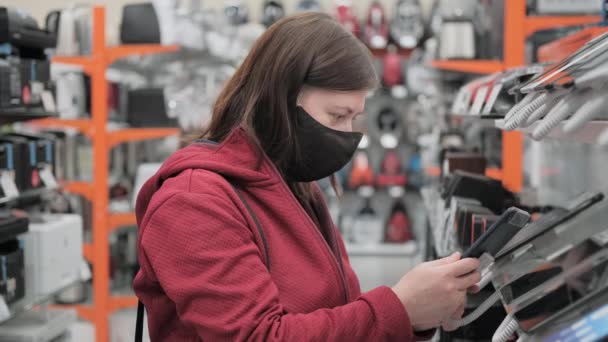 Girl in medical mask buys tablet pad in shop — Stock Video