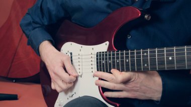 Adam elektro gitarın alt telini çalıyor.