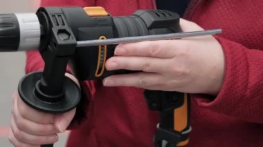 Kız bir alet dükkanından elektrikli matkap alıyor.