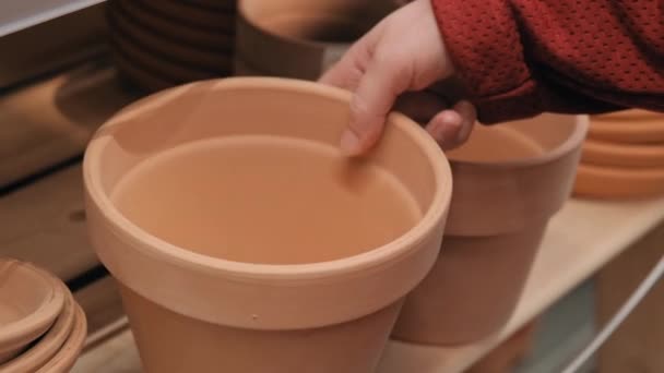 Girl potter puts a pot after firing on a wooden shelf — Stock Video