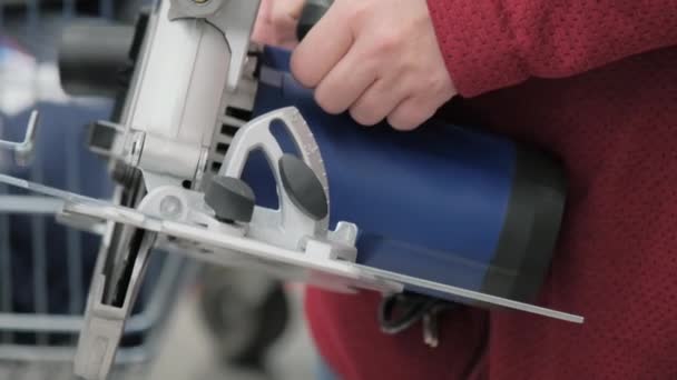 Girl in a shop buys a big hand held, electric circular saw — Stock Video