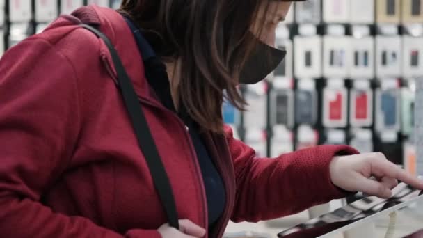 Маскарадна жінка купує планшет у сучасному магазині електроніки — стокове відео