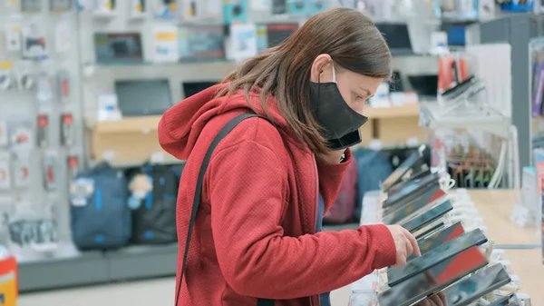 Maskeli kız aygıt deposundan ve aygıtlardan yeni tablet seçiyor