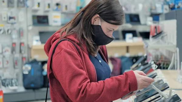 Maskeli kız elektronik cihazlardan akıllı telefon seçer