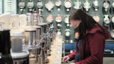 Koruyucu maskeli hamile bir kadın dükkanda mikser seçiyor.