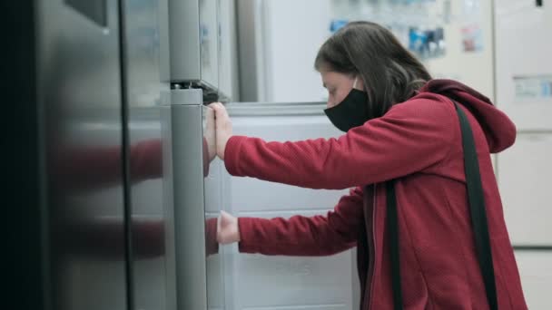 女の子で医療マスクでウイルスに対する店で冷蔵庫を購入 — ストック動画