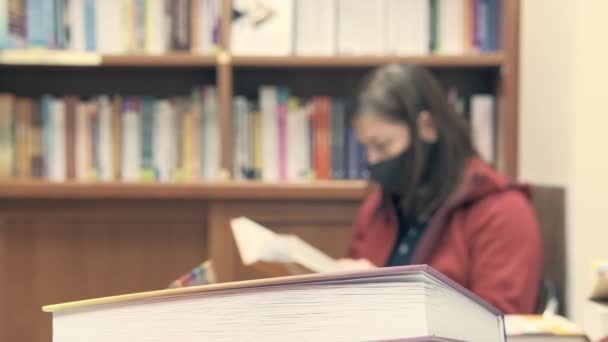 Frau liest in Bibliothek. Sie in Unschärfe, Fokus steht im Vordergrund — Stockvideo