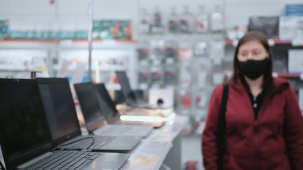 Meisje met masker en handschoenen koopt laptop in een elektronicawinkel — Stockvideo
