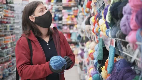 Frau mit Maske und Handschuhen kauft Chenille-Garn zum Stricken — Stockvideo