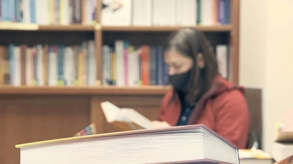 Woman reads in library. She in blur, focus is in foreground — Stock Photo, Image