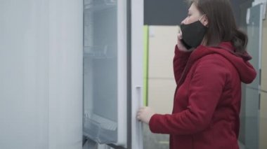 Maskeli kız bir ev gereçleri dükkanından buzdolabı alıyor.