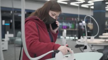 Maskeli kadın dükkanda kıyafet için ütü sistemi seçiyor.