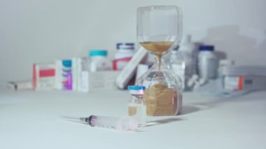 Arka plandaki kum saatinde aşı ve şırınga.