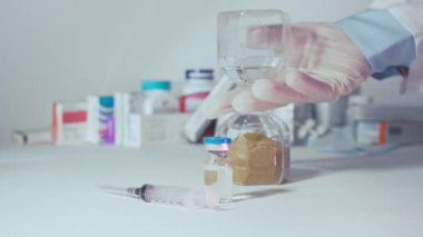 Doktor kum saatini çeviriyor. Aşı ve şırınga önde.