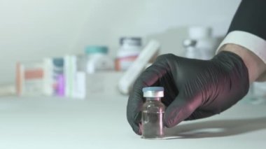 Eldivenli el aşıyı ve şırıngayı bırakıp onları işaret ediyor.