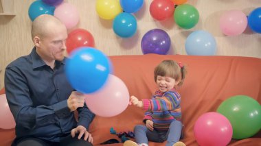 Baba ve kızı balonlarla kavga ediyor. Eğleniyorlar, gülüyorlar.