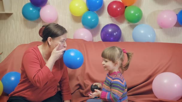 Young grandmother inflates balloon and plays with her little granddaughter — Stock Video