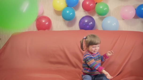 Grappig klein meisje met paardenstaarten op haar hoofd spelen met ballonnen — Stockvideo
