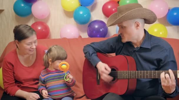 Мама, тато і маленька дитина грають на гітарі співають, танцюють і розважаються — стокове відео