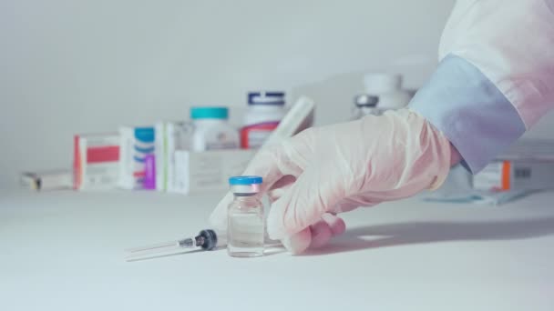 Hand in medical gown picks up vaccine and syringe from table — Stock Video