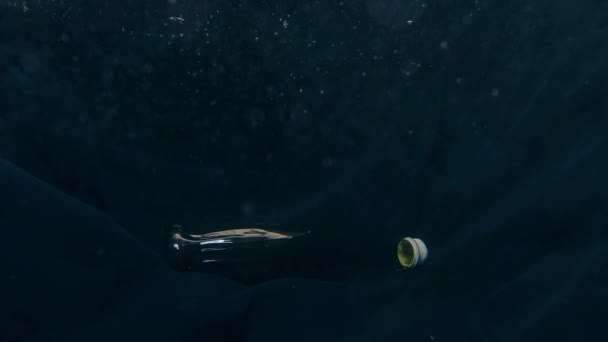 Man hand pulls out a glass bottle with a soft drink from the water — Stock Video