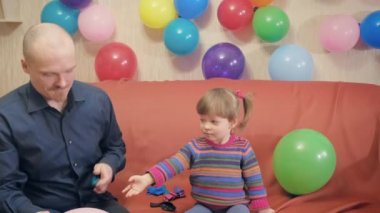 Baba ve kızı balonları şişirip onlarla oynuyorlar. Memnun ve mutlular.