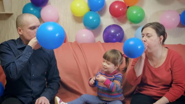 Папа, мама и маленькая девочка синие надутые шарики на день рождения — стоковое видео