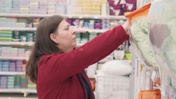 Een vrouw in de winkel koopt een warme deken. Ze houdt van het beddengoed glimlacht ze goedkeurend — Stockvideo