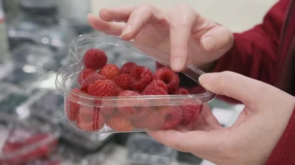 Girl hands in the shop buys a with large, ripe, red raspberries. Close up shot — Stock Video