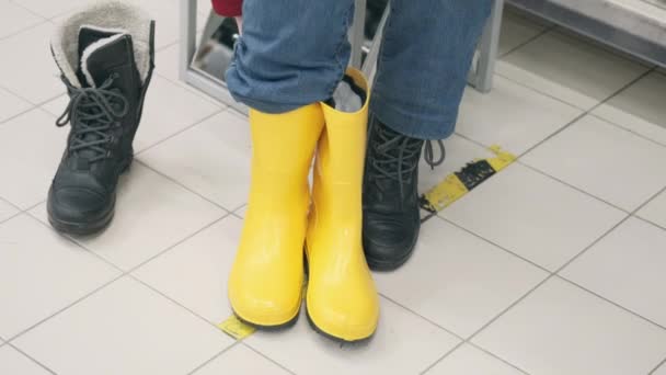 Mujer caucásica compra botas de goma en la tienda. Concepto de lluvia intensa. Primer plano. — Vídeo de stock