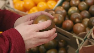 Dükkandaki kadınlar taze, olgun, siyah, sarı, kırmızı domateslerle alıyorlar. Kapat.