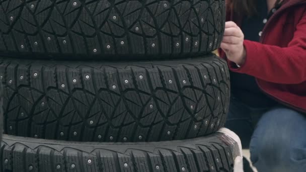 Mulher caucasiana escolhe pneus cravejados para carro na loja. Conceito de gelo nas estradas — Vídeo de Stock