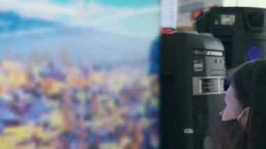 Virüse karşı maskeli bir kız dükkanda büyük bir televizyona benziyor. TV ekranı çok bulanık