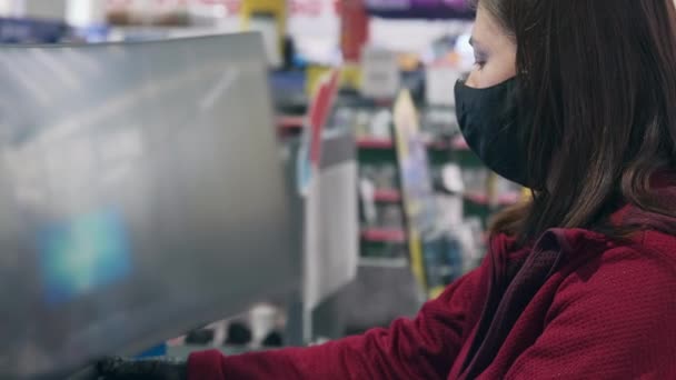 Meisje draagt masker en handschoenen tegen virus koopt concave monitor in winkel gadgets — Stockvideo