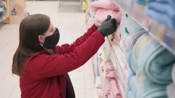 Вумен в маске и перчатках против вируса покупает Терри, розовое полотенце для душа в магазине — стоковое видео