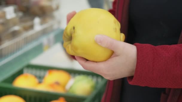 Meisjes in de winkel kopen een met grote, rijpe kweepeer. close-up schot — Stockvideo