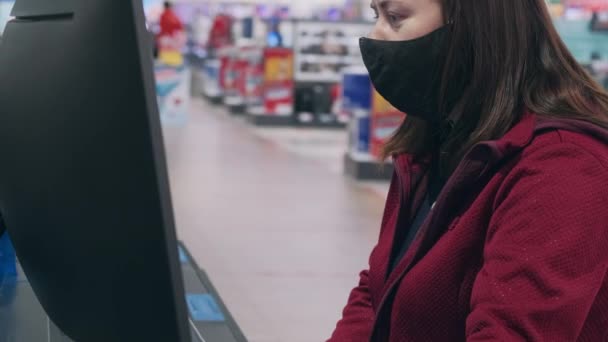 Девушка в маске и перчатках против вируса покупает вогнутый монитор в магазинах — стоковое видео