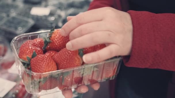 Kobieta wybiera świeże truskawki w sklepie. Strzał z bliska z jagód i rąk — Wideo stockowe